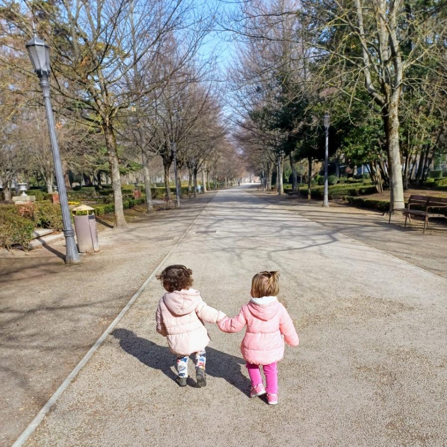 Niñas de la mano paseando por un parque