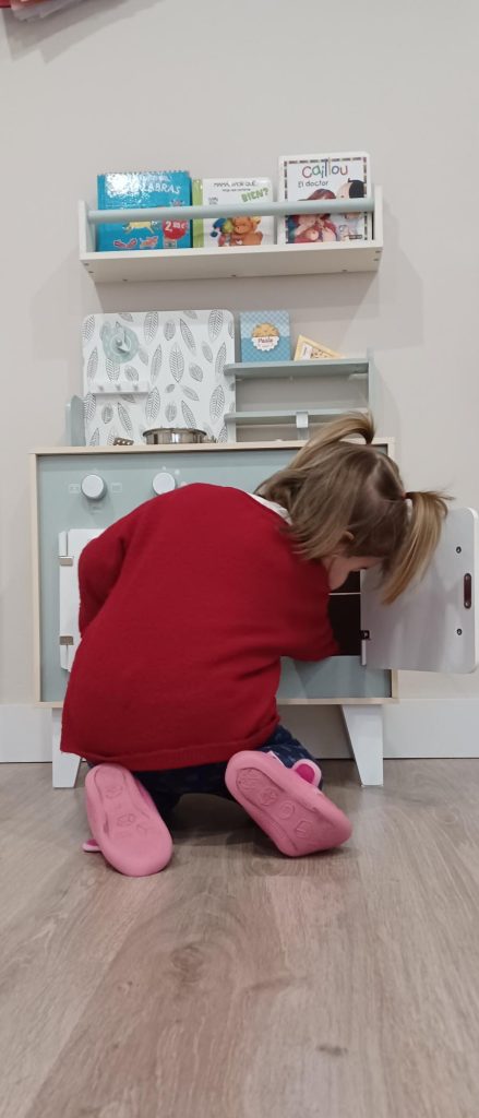 Niña jugando con una cocina de juguete